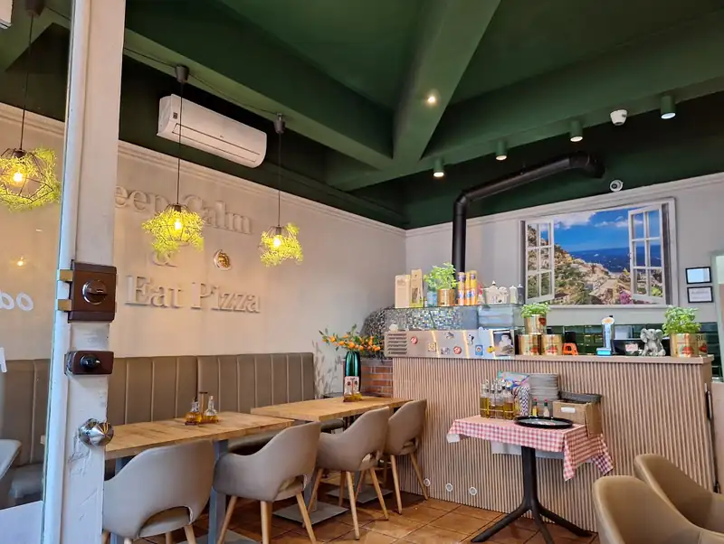 Sala z zielonym sufitem, lampami i napisem Keep calm & Eat Pizza